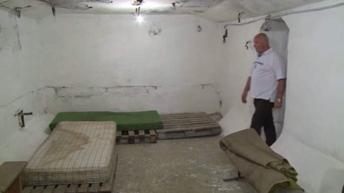 Vitaly Dubinin, local resident walks in the bomb shelter in Lugansk, eastern Ukraine (screenshot from RT video)